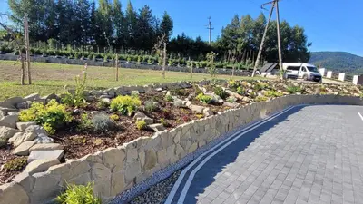 a garden with a stone wall next to a road at Apartamenty Home&Spa in Rabka