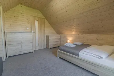 a bedroom with a bed in a wooden cabin at Wycisznia - drewniane domki całoroczne in Gierałtowiczki