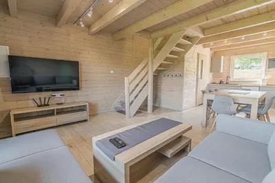 a living room with a television and a staircase at Wycisznia - drewniane domki całoroczne in Gierałtowiczki