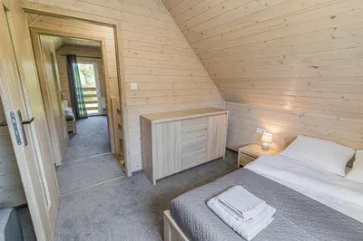 a bedroom with a bed in a wooden cabin at Wycisznia - drewniane domki całoroczne in Gierałtowiczki