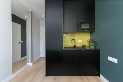a kitchen with black cabinets and a sink at Smart Apartments - Old Town & Main Train Station - by Upstairs in Kraków