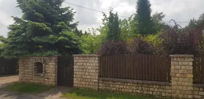 a brick fence with a gate in a yard at Szyszka i Róża Domek na Jurze in Zelasko