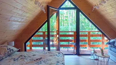 a bedroom in a tree house with a large window at Las Lorien - wynajem domków letniskowych in Roczyny