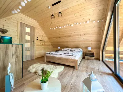 a bedroom with a bed in a wooden cabin at Las Lorien - wynajem domków letniskowych in Roczyny