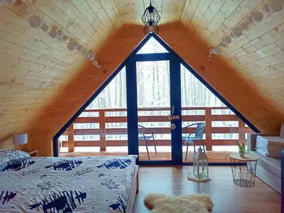 a bedroom with a large window in a cabin at Las Lorien - wynajem domków letniskowych in Roczyny