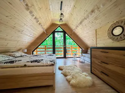 a attic bedroom with a bed and a large window at Las Lorien - wynajem domków letniskowych in Roczyny