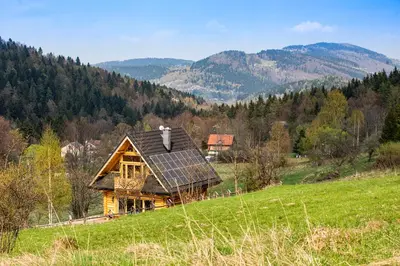 a house with a solar roof on a green field at Pyrgielówka- chata Roztoki in Stryszawa