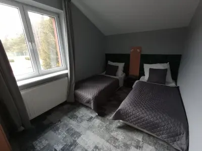 a bedroom with two beds and a chair and a window at Agroturystyka AMiG in Krzywopłoty