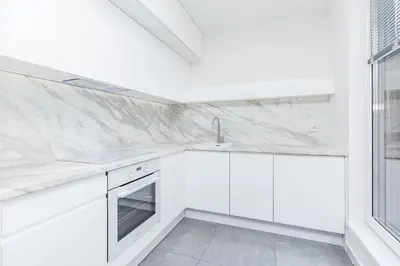 a white kitchen with white cabinets and a sink at Apartments Browar Kleparz by Noclegi Renters in Kraków