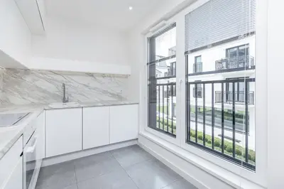 a kitchen with white cabinets and a large window at Apartments Browar Kleparz by Noclegi Renters in Kraków