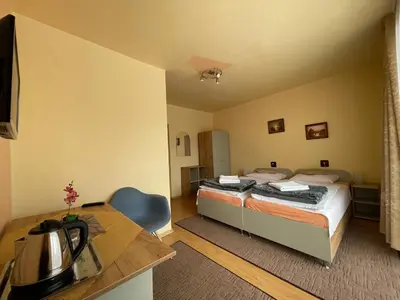 a room with two beds and a desk with a kitchen at Dom Wczasowy Anna in Rabka