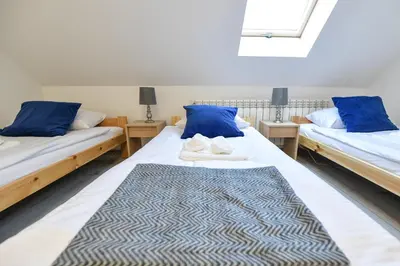 a bedroom with two beds with blue pillows and a window at Toffee House in Zator