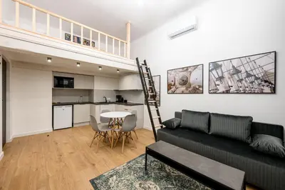 a living room with a black couch and a kitchen at Native Apartments Paulińska 20 Superior in Kraków