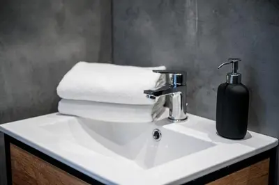 a bathroom sink with a black soap dispenser on it at Native Apartments Paulińska 20 Superior in Kraków