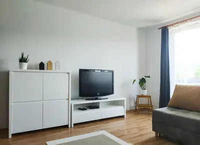 a living room with a tv on a white cabinet at Uroczy Apartament Pod Skarpą in Wadowice