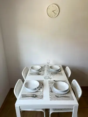 a white table with chairs and a clock on the wall at Uroczy Apartament Pod Skarpą in Wadowice