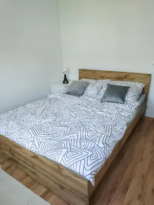 a bed in a room with a white wall at Uroczy Apartament Pod Skarpą in Wadowice