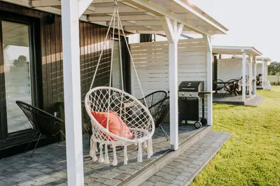 a porch with two wicker chairs and a grill at Domki Energylandia Zator Przybradz in Przybradz