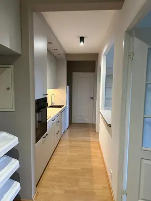 a kitchen with white cabinets and a wooden floor at Dekoratoria Apartments in Kraków