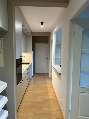 a kitchen with white cabinets and a wooden floor at Dekoratoria Apartments in Kraków