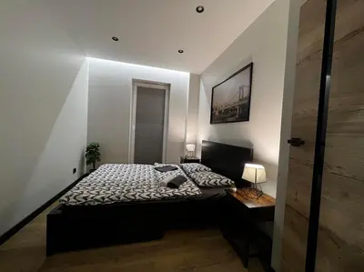a bedroom with a bed and a table with a lamp at Apartament Helsinki in Zator