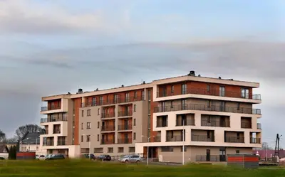 a tall building with cars parked in front of it at Apartament Helsinki in Zator