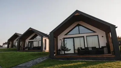 a row of houses with windows on a lawn at Tulichatki domki całoroczne in Tarnawa Dolna