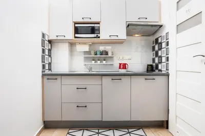 a kitchen with white cabinets and a sink at City of the Kings - Old Depot Apartment in Kraków