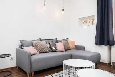 a living room with a gray couch and two tables at City of the Kings - Old Depot Apartment in Kraków