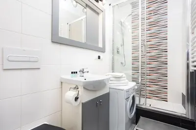 a white bathroom with a sink and a washing machine at City of the Kings - Old Depot Apartment in Kraków