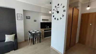 a room with a table and a clock on a wall at Apartament KoraZone 2 ZATOR in Zator