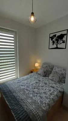 a bedroom with a bed and a window and a lamp at Apartament KoraZone 2 ZATOR in Zator