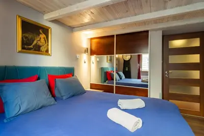 a bedroom with a blue bed with a mirror at Lilly apartment main train station old town by The Heritage House Main Square Cracow in Kraków