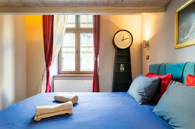 a bedroom with a blue bed with a clock on the wall at Lilly apartment main train station old town by The Heritage House Main Square Cracow in Kraków