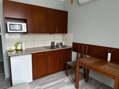 a kitchen with wooden cabinets and a sink and a table at Kompleks Apartament-Serwis in Kraków