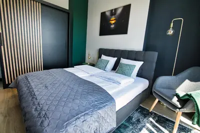a bedroom with a large bed and a chair at Apartament Proste Chwile 38 by Housine in Zator