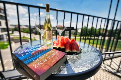 a glass table with a bottle of wine and watermelon and a book at Apartament Proste Chwile 38 by Housine in Zator