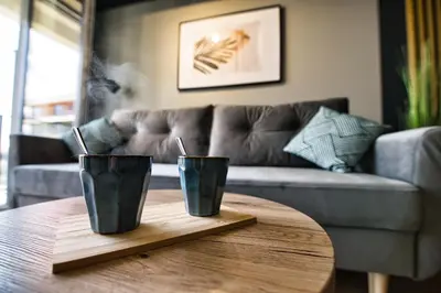 two black cups on a wooden table in front of a couch at Apartament Proste Chwile 38 by Housine in Zator