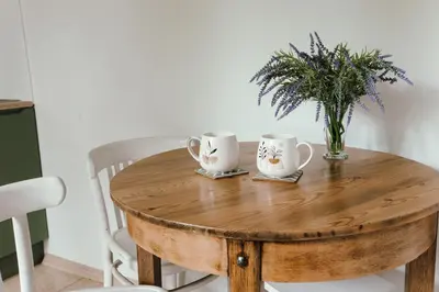 a wooden table with two cups and a vase on it at Leśne zacisze - dom z kominkiem i balią in Jordanów