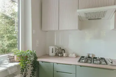 a white kitchen with a stove and a window at Leśne zacisze - dom z kominkiem i balią in Jordanów