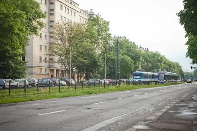 an empty street with cars parked on the side of the road at Apartament Nowa Huta in Kraków