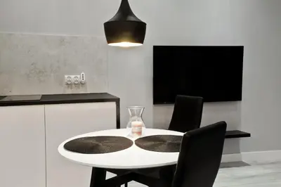 a dining room with a white table and black chairs at Apartament Nowa Huta in Kraków