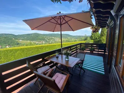 a wooden deck with a table and chairs and an umbrella at Urlopowa Chata in Targanice