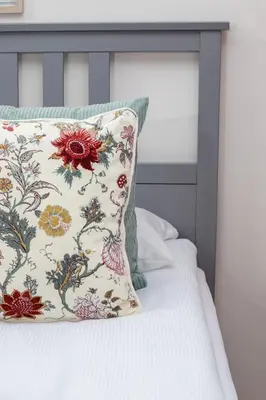 a pillow sitting on a bed with a floral pillow at Deluxe Studio Cracow Ariańska by Noclegi Renters in Kraków