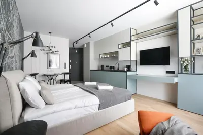 a white bedroom with a large bed and a kitchen at Deluxe Studio Cracow Ariańska by Noclegi Renters in Kraków