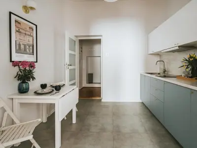 a white kitchen with a table and a chair at S18 Apartments in Kraków