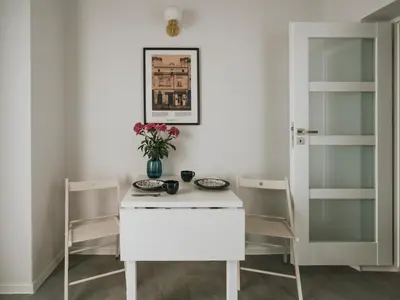 a white table with two chairs and a vase with flowers at S18 Apartments in Kraków