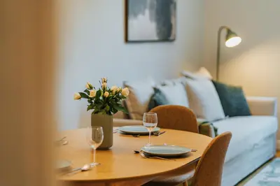 a wooden table with two glasses and a vase of flowers at S18 Apartments in Kraków