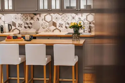 a kitchen with a counter with white bar stools at S18 Apartments in Kraków