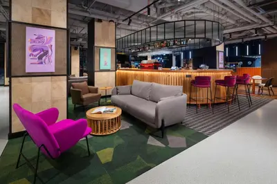 a living room with a couch and chairs and a bar at Hyatt Place Krakow in Kraków